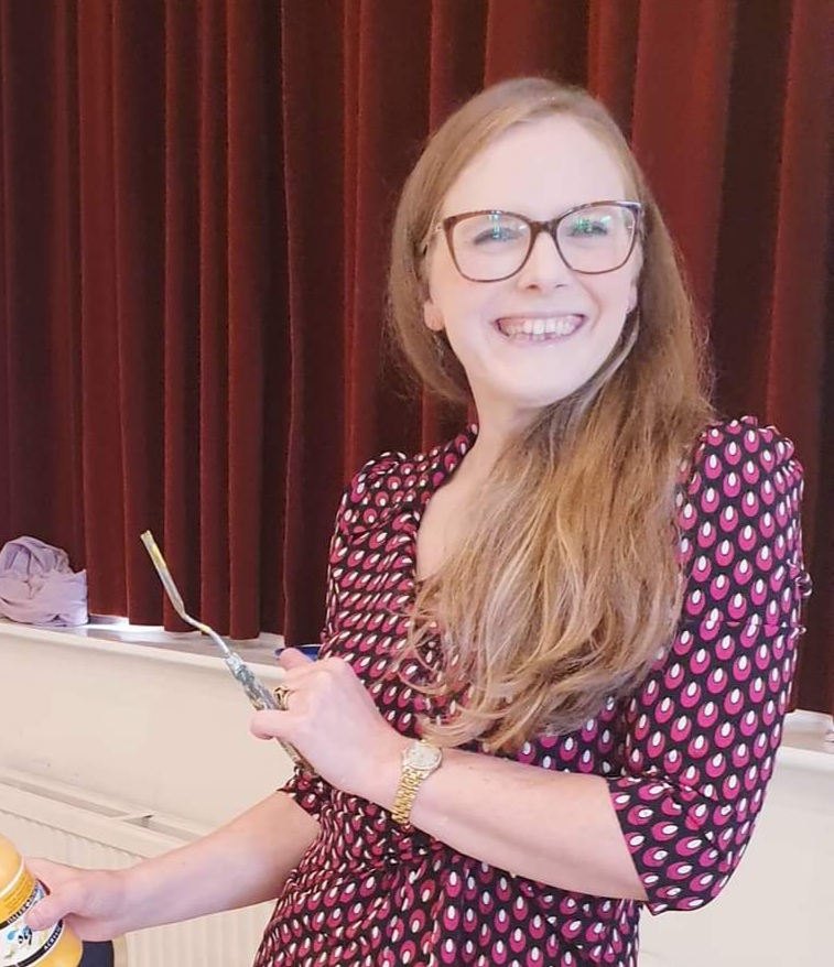 Head-and-shoulders view of the artist who smiles, holding a palette knife