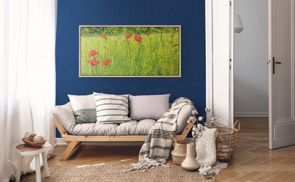 View of a large, bright painting with greens and red poppies, set in an interior with sofa and dark blue wall